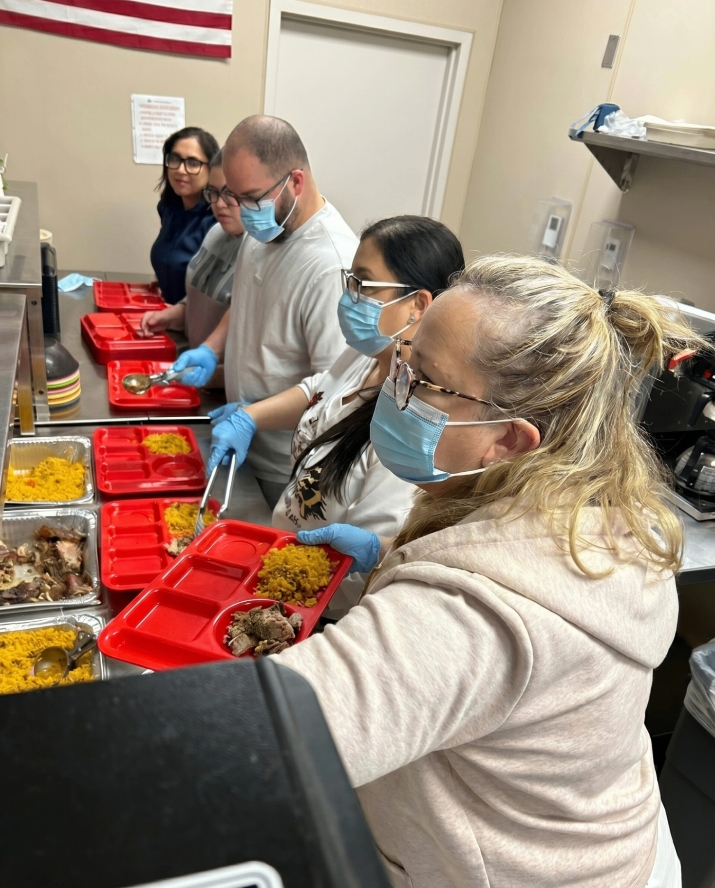 Carmen Ruiz volunteering, serving food trays at a community kitchen